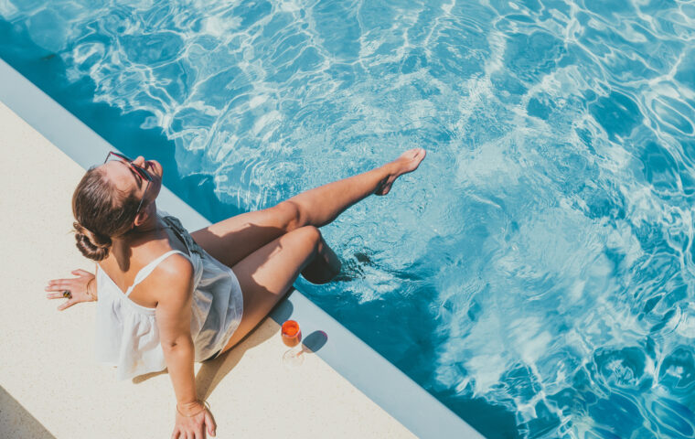 Fashionable woman sitting by the pool on the empty deck of a cruise liner. Closeup, outdoor, view from above. Vacation and travel concept